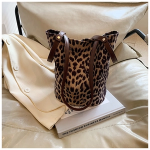 Close-up of leopard print bucket bag with leather handle on a fashion business book