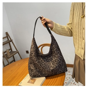 Detail of vintage leopard print tote bag with black leather shoulder strap held by model