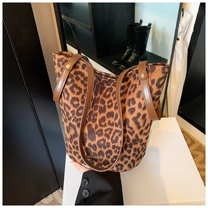 Detail view of leopard print bucket tote bag with brown leather straps on display stand