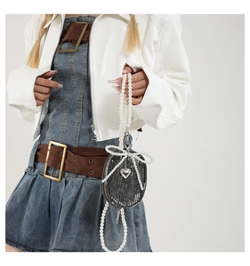 Détail du mini sac bandoulière en jean avec nœud perlé, paillettes et pendentif cœur