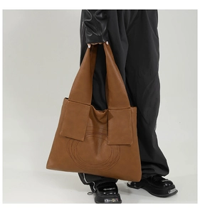 Detailed close-up of large brown tote bag with circular stitching and pebbled leather texture