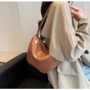 Detail view of the knotted shoulder strap and vintage brown leather texture on bucket bag