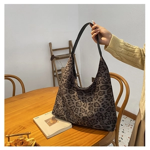 Detailed view of leopard print canvas hobo bag with a black leather handle in home setting