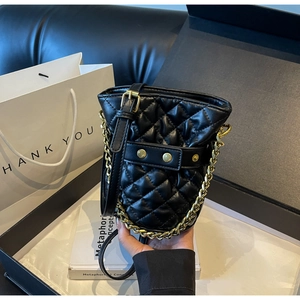 Detail view of black quilted bucket bag with gold chain and luxury gift packaging set