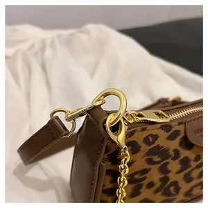 Close-up of leopard print fabric texture with dark brown leather trim and gold metal hardware