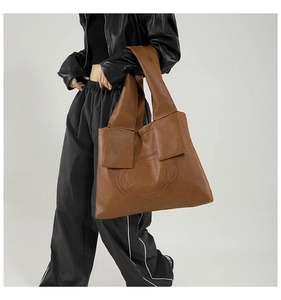 Detailed texture of brown faux leather tote with unique spiral stitching and wide strap