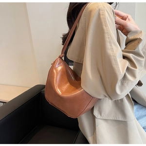 Detail of caramel brown leather shoulder bag with knotted strap and metal zipper closure