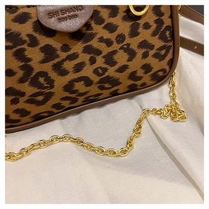 Close-up of leopard print shoulder bag with gold chain strap and brown leather trim