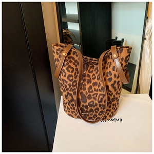 Detail of leopard print tote bag with brown leather handles and gold metal rivets