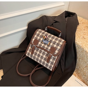Detail of British plaid backpack with dog embroidery leaning on a black suit jacket