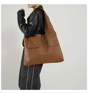 Close-up of brown faux leather tote bag with circular stitching worn by model