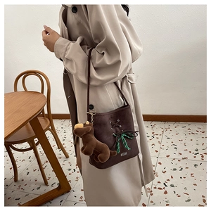 Detail of dark brown suede bucket bag with ribbon and cute plush dog charm