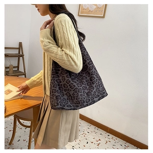 Detail view of large leopard print tote bag carried by model in a minimalist room