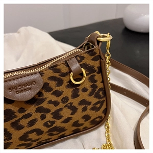 Detailed macro view of leopard print fabric texture and gold hardware on the crossbody bag