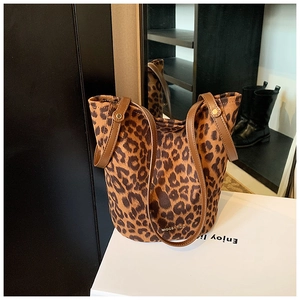 Detail view of leopard print bucket bag with brown faux leather strap and metal rivets
