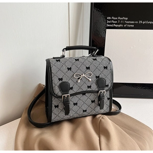 Detail of woven mini backpack with black bow embroidery and silver metal hardware