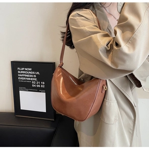 Detail of caramel brown bucket bag with a knotted shoulder strap worn by a model