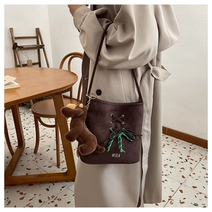 Detail of dark brown suede bucket bag with lace-up design and plush dog charm