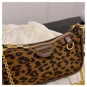 Detailed view of leopard print texture with gold zipper and chain strap on underarm bag