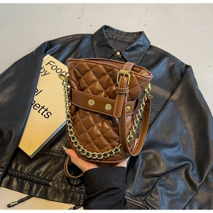 Detail of vintage brown quilted bucket bag with gold chain and metal rivets on leather