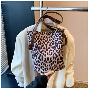 Detail view of leopard print bucket bag with leather handles and metallic rivet accents