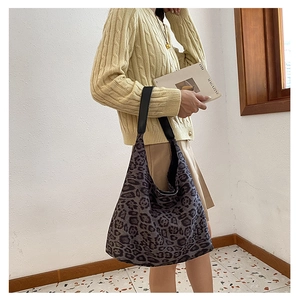 Close-up of a large leopard print canvas tote bag with black wide straps on a fashion model