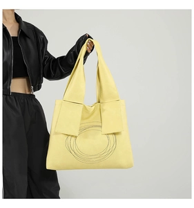 Detail of yellow tote bag featuring concentric circle stitching and wide flat handles