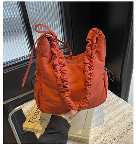 Detail van oranje nylon hobo tas met ruches aan de riem en verstelbaar trekkoord