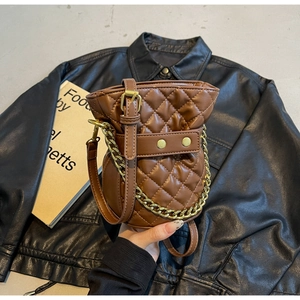 Macro detail of brown quilted bucket bag with gold chain and metal hardware accents