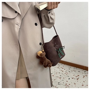 Close-up of brown faux suede bucket bag with green lacing and cute dog bag charm detail