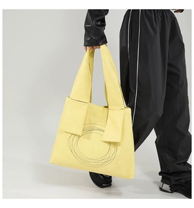 Detail of a bright yellow tote bag with concentric circular quilting and wide strap base