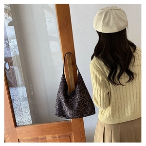 Detail of soft leopard print tote bag styled with knit sweater and pleated skirt