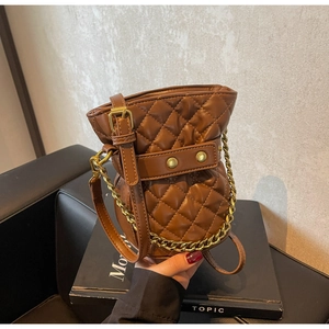 Detail of brown quilted bucket bag with gold chain strap and drawstring closure