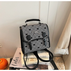Detail of grey quilted backpack with black bows and silver metal bow pendant