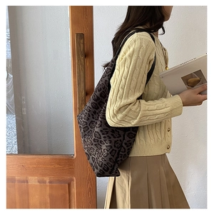 Close-up of leopard print tote bag paired with vintage knit cardigan and pleated skirt