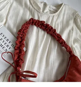 Gros plan du sac nuage rouge brique avec cordon de serrage et bandoulière plissée