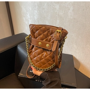 Close-up of brown quilted leather bucket bag with gold chain strap and metal rivet details