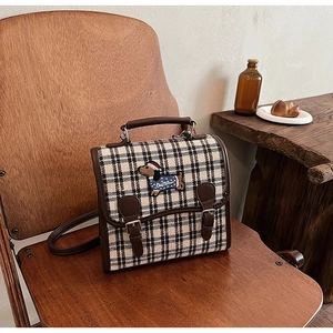 Detail of British style plaid handbag with leather trim and cartoon dog embroidery