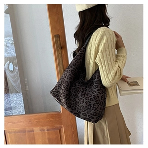 Detail of leopard print hobo bag worn by a model in casual knitwear and skirt