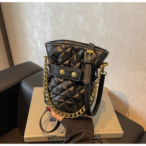 Detailed view of the quilted bucket bag featuring a gold chain handle and drawstring closure