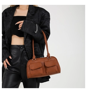 Detail showing brown leather underarm bag with dual front pockets and silver ring hardware