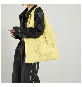 Detail of large yellow tote bag with unique circular stitching and side pockets