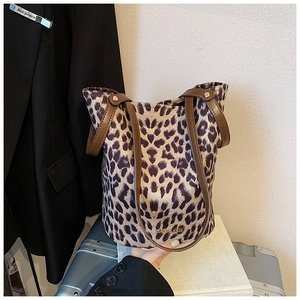 Detail of leopard print bucket bag with brown leather handles and brand logo