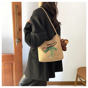 Detail of suede bucket bag with woven bow knot and cute plush bear charm