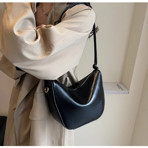 Detail of black faux leather hobo bag with unique knot shoulder strap and golden buckle
