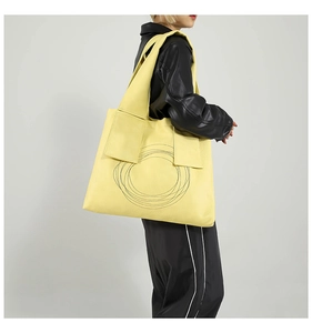 Detail view of yellow PU leather tote bag with unique black spiral pattern and wide shoulder strap