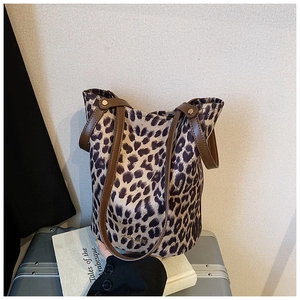 Detail view of leopard print bucket bag with brown leather handles and gold metal logo