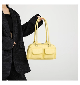 Detail of yellow leather shoulder bag with two front pockets on a model wearing black