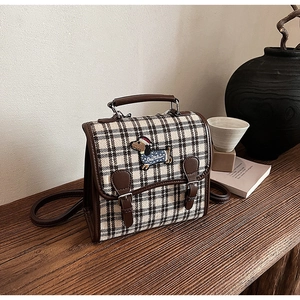 Detailed view of British vintage plaid backpack with embroidery on solid wood table