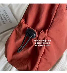 Détail de poche latérale à cordon sur sac rouge brique pour un accès facile et pratique
